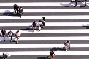 Persone viste dall'alto che camminano su strisce pedonali. Immagine di copertina di un articolo di Secondo Welfare sulle proposte dell'Alleanza contro la povertà per andare oltre il Reddito di Cittadinanza