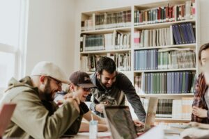 Tre ragazzi ridono dentro una biblioteca, un nuovo luogo di welfare socio-culturale